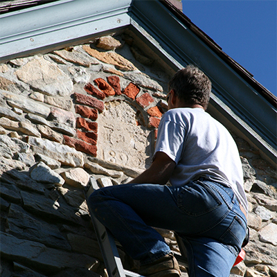 a man observing an old date stone in need of repair