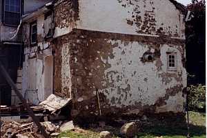 An old dilapidated home with a vent sticking out the wall for a bake oven