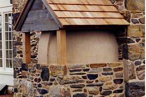 Looking at the outside of a squirrel tail bake oven with a new enclosure