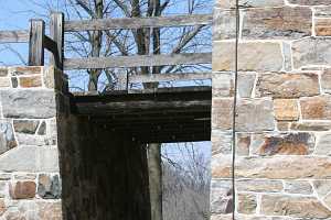 a bridge between a barn and a natural stone wall