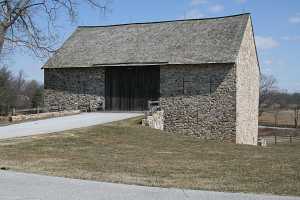 a historic stone barn and a rebuilt natural stone bridge
