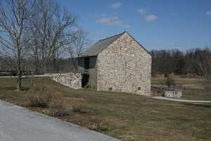 a historic stone barn and a rebuilt natural stone bridge