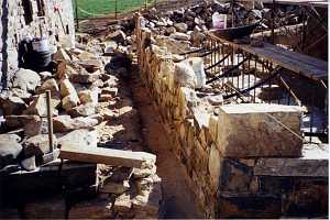 scattered stones and tools next to a natural stone wall that is being built