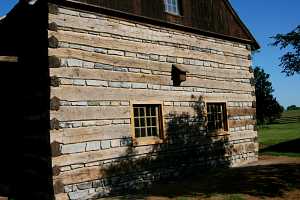 new wall of a log cabin with custom cut stones