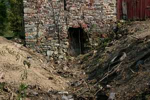 eroded land around a damaged wall of an old barn