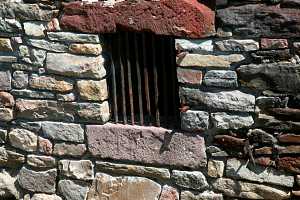 a rusted grate in the stone wall of a barn