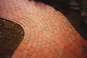 a rounded corner of a brick patio with planting areas around it