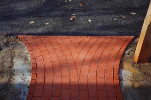 a rounded brick pattern leading to an asphalt driveway