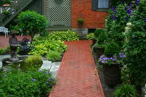 a brick patio area that includes a pond and many planters, shrubs and other outdoor features