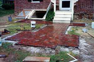 a small brick walkway leading to a steps and door as well as a cellar