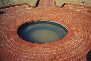 a round pond in the middle of a brick patio