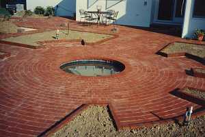 a newly installed brick patio with a round pond in the middle