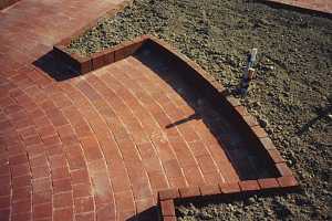 a brick patio and garden with dirt