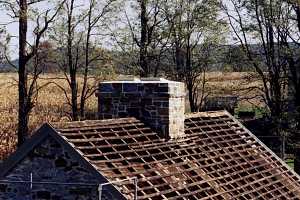 A stone chimney and roof without shingles