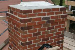 A restored brick chimney and a roof repair in progress