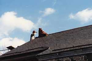 A man providing chimney services to a broken brick chimney