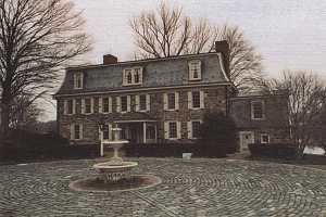 An old circular cobblestone driveway and home in need of repair