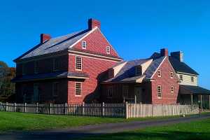 a restored brick home with a picket fence in the front yard