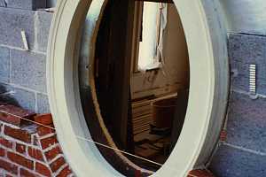 a rounded window on a brick home with the upper part of the wall being repaired