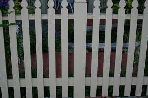 a brick walkway around a white picket fence with a gazebo in the background