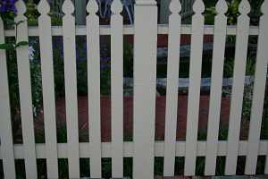 a brick walkway around a white picket fence with a gazebo in the background