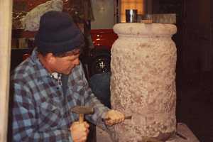 A stonemason beginning to form an outdoor sundial pillar