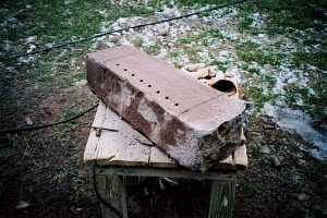 A stone being shaped for a custom grate replacement with grate holes drilled