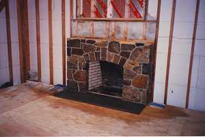 a natural stone fireplace with a wall frame and no drywall around it