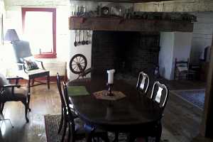 a historic kitchen with a brick fireplace in the background