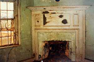 an old fireplace area with vines growing in the window beside it - before