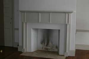 an empty fireplace with tan mantel