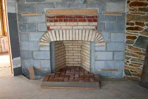 a fireplace of bricks in between a cinder block wall - before