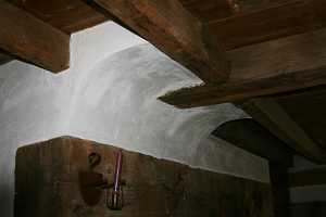 wall above a fireplace running into wooden rafters