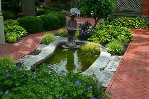 a fish pond with a small boy statue on the edge and some water plants and fish in it