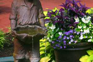 a small boy water fountain in a fish pond next to a decorative planter