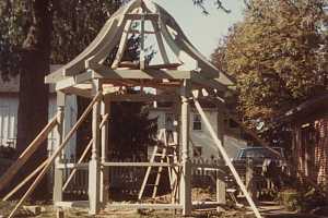 a wooden gazebo with framing posts and the top framed out