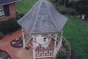 a brand new gazebo complete with a brick walkway, fish pond, furniture and gardens