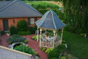 a brand new gazebo complete with a brick walkway, fish pond, furniture and gardens