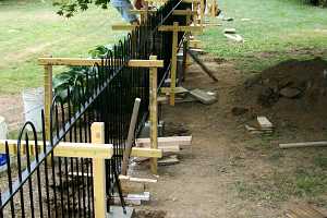 two men installing a black iron fence