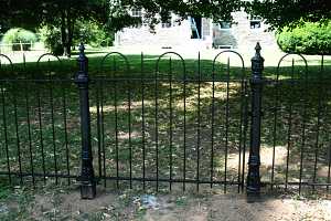 a black iron fence in front of a stone home