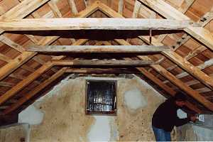 The inside of an old spring house with a man working on the stone