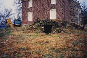 An underground spring house next to a brick and stone home