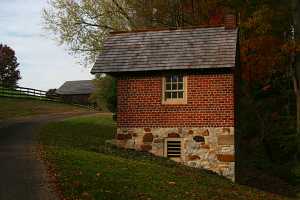A fully restored red brick spring house with a stone base