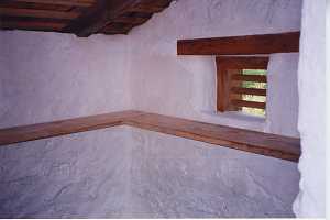 The inside corner of a restored spring house looking at shelving and a window