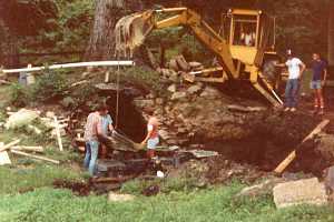 A yellow backhoe moving supplies for a spring house repair