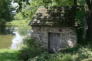 A restored stone spring house next to a pond