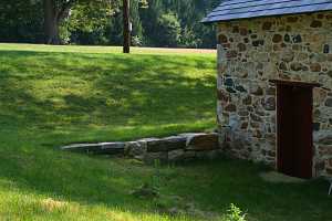 A fully restored stone spring house with red door