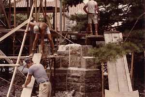 Workers developing scaffolding in preparation for custom stone transport to an archway