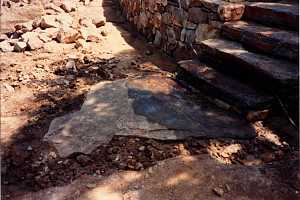 a stone retaining wall and stone steps leading down to a flagstone landing