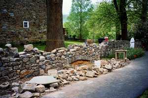 the rebuilding of a stone wall. dozens of stones lay in front with two buckets